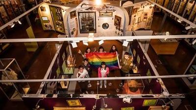 Aerial view of people in Lynn museum holding a Pride flag 