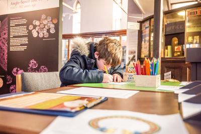 A child sat colouring at the museum