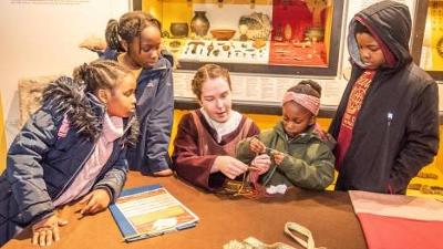 Adult and children looking and interacting with textile threads